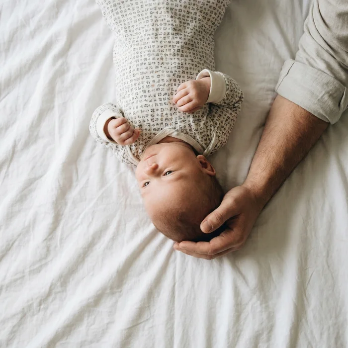 Rejected baby passport photo example — a hand in the frame